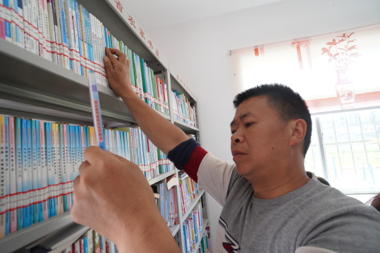 王兴龙在化甲村农家书屋里寻找果树种植书籍.JPG