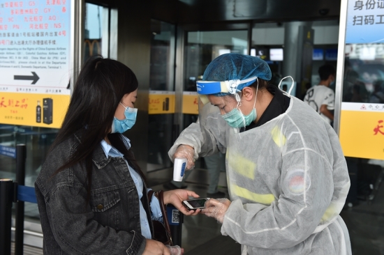 机场大厅外疫情防控工作人员正在对乘客做体温检查.jpg