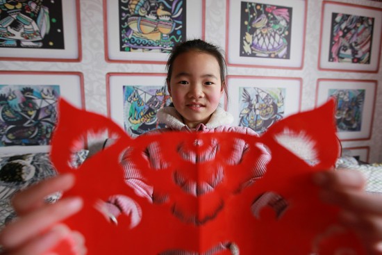 贵州省毕节市黔西县春晖剪纸艺术班的孩子展示创作的迎春作品.jpg